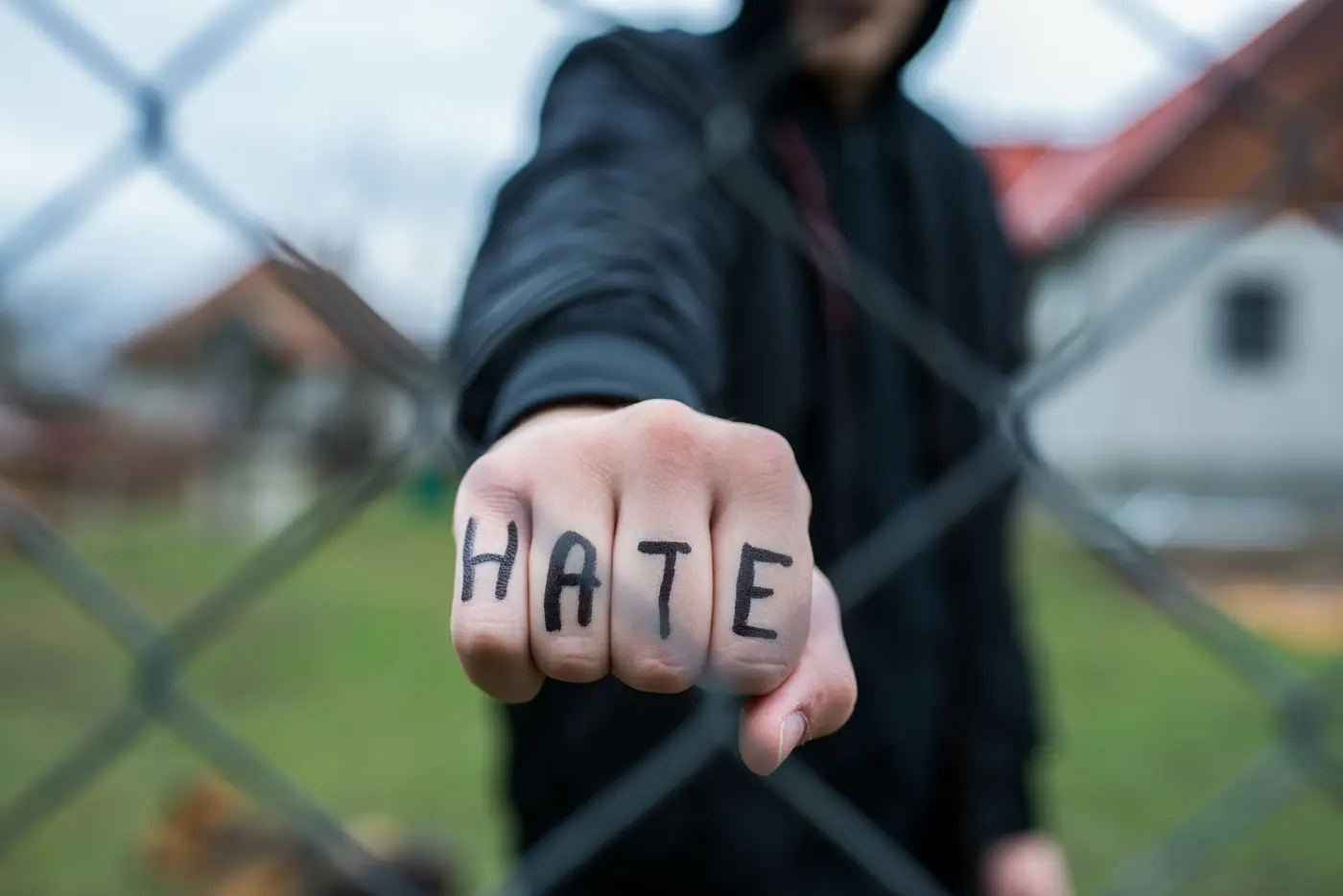 Aggressive teenage boy showing hes fist behind wired fence at th
