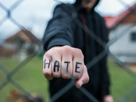 Aggressive teenage boy showing hes fist behind wired fence at th