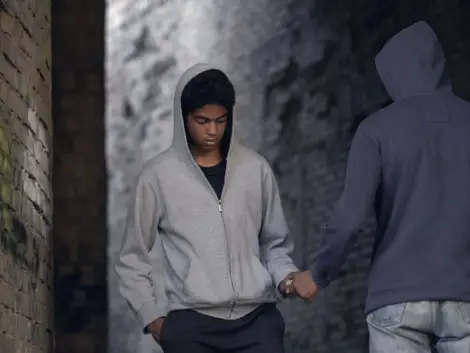 Young black men exchanging money to drugs in abandoned building, addiction