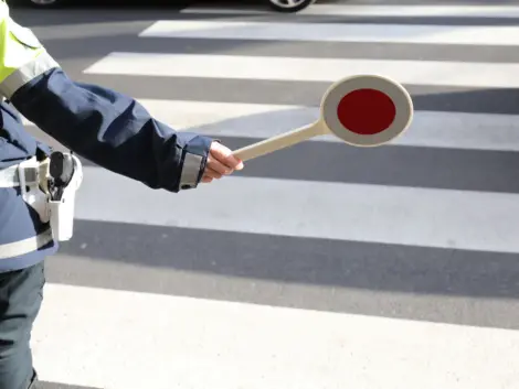 policeman with the paddle to stop the car on the pedestrian crossing